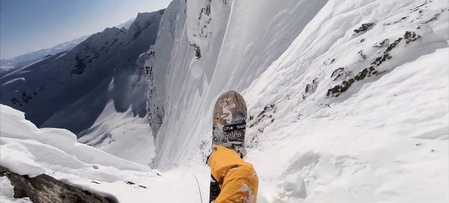 Insane guy rappels down a vertical rock wall to snowboard at hyperspeed