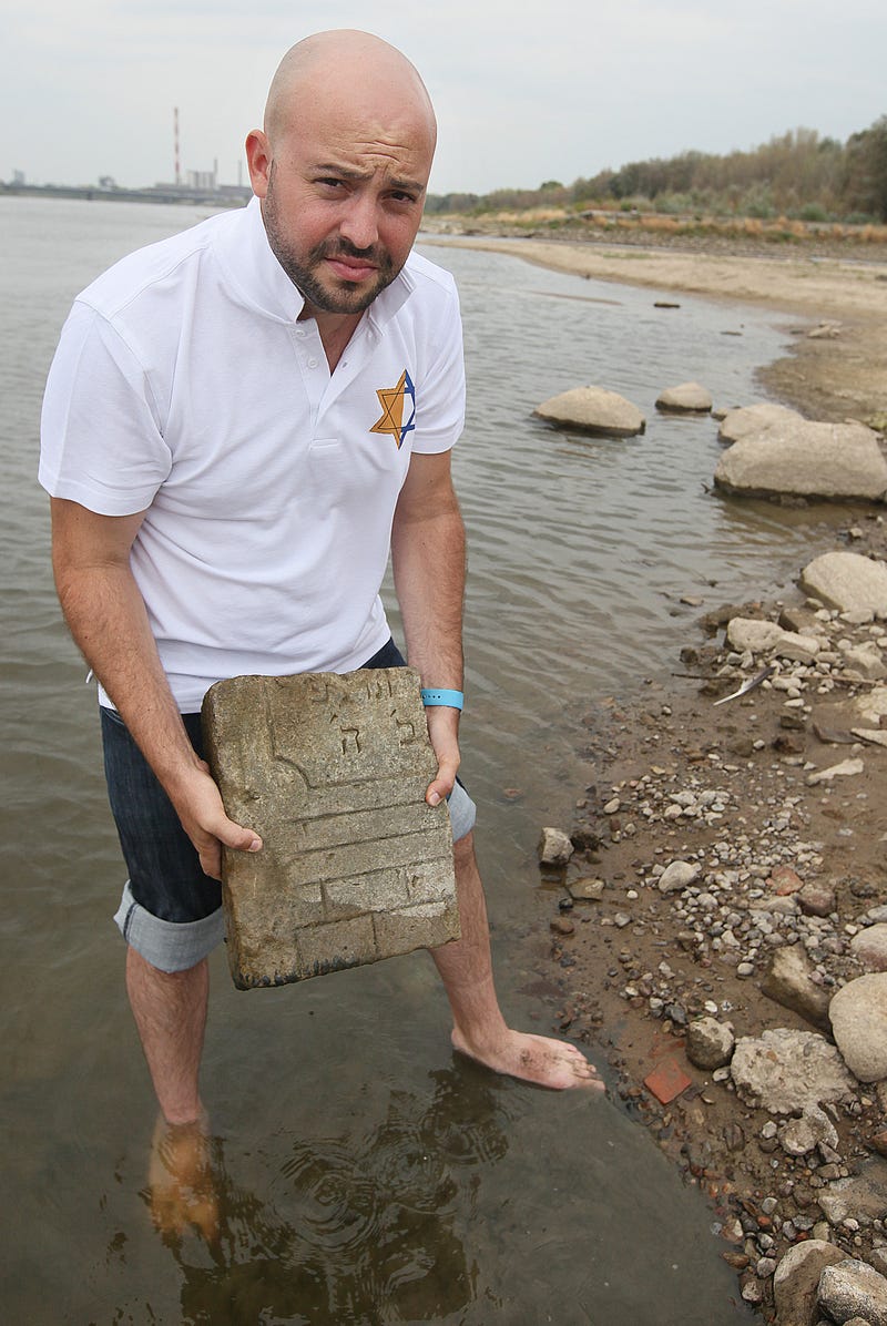 Jonny Daniels, who runs a foundation called “From the Depths,” holds a tombstone found in the Vistula. AP Photo/Czarek Sokolowski.