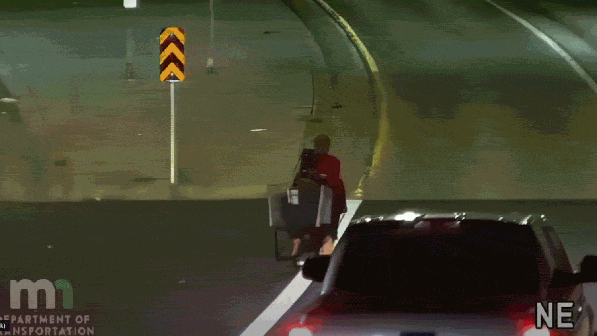Frau mit Tasche auf dem Kopf fährt mit motorisiertem Einkaufswagen auf die Autobahn