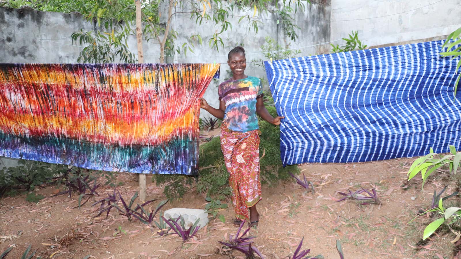 A Sierra Leone clothing design worker poses with tie-dyed fabrics. The country recently passed a law ensuring women can access bank loans.