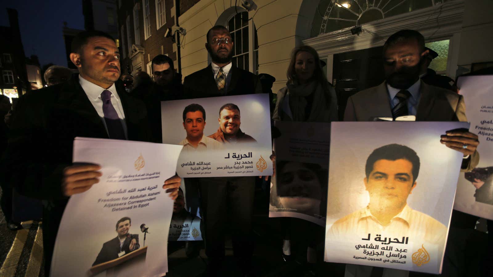 Protesters gather outside Egypt’s embassy in London with photos of the Al Jazeera reporters.