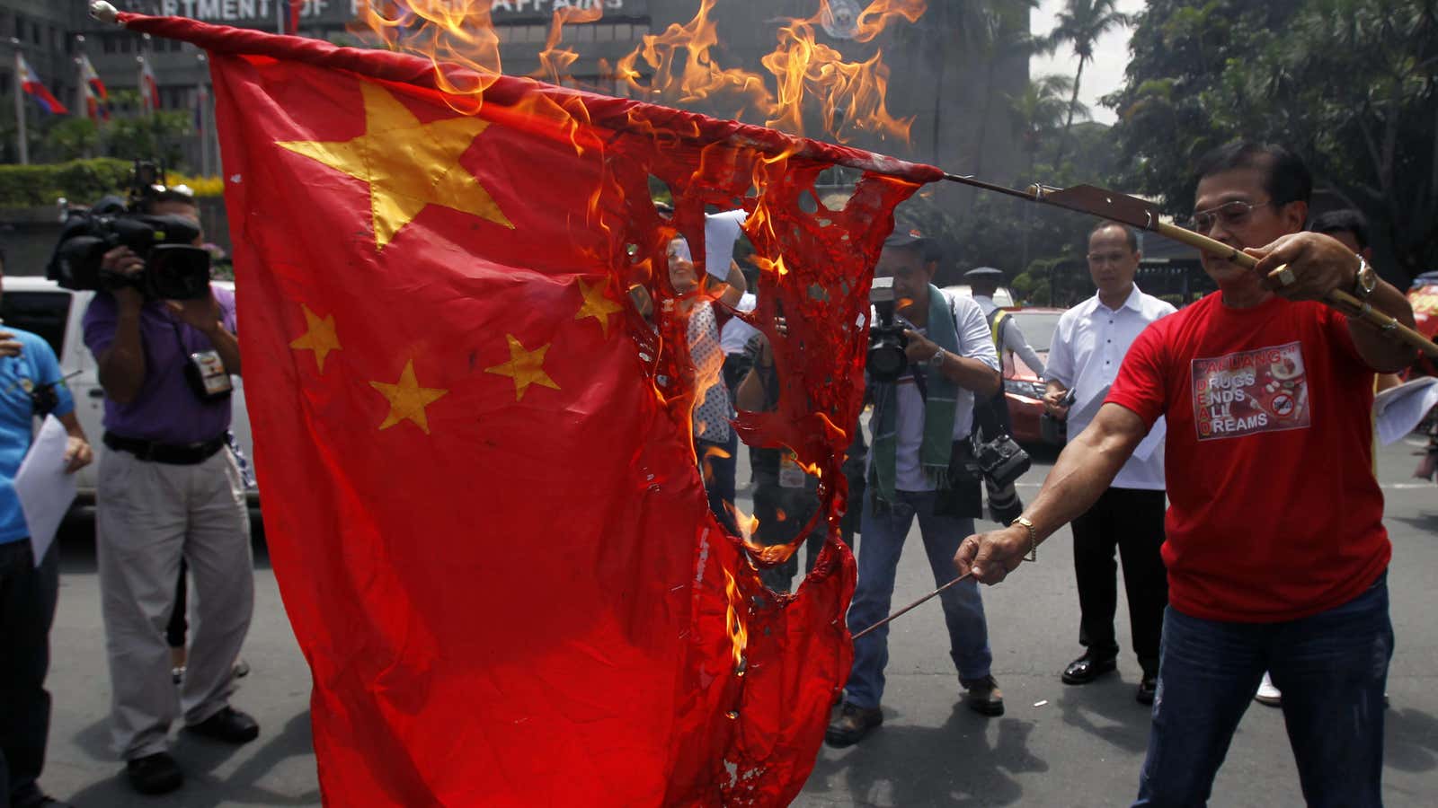 Abner Afuang, a former local mayor and policeman, burns a Chinese flag during a protest in front of the Department of Foreign Affairs headquarters in…