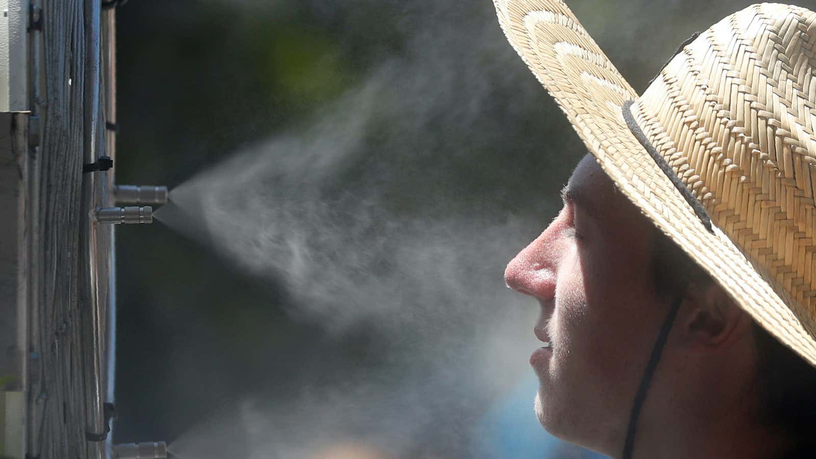 A man cools off in front of a misting fan.