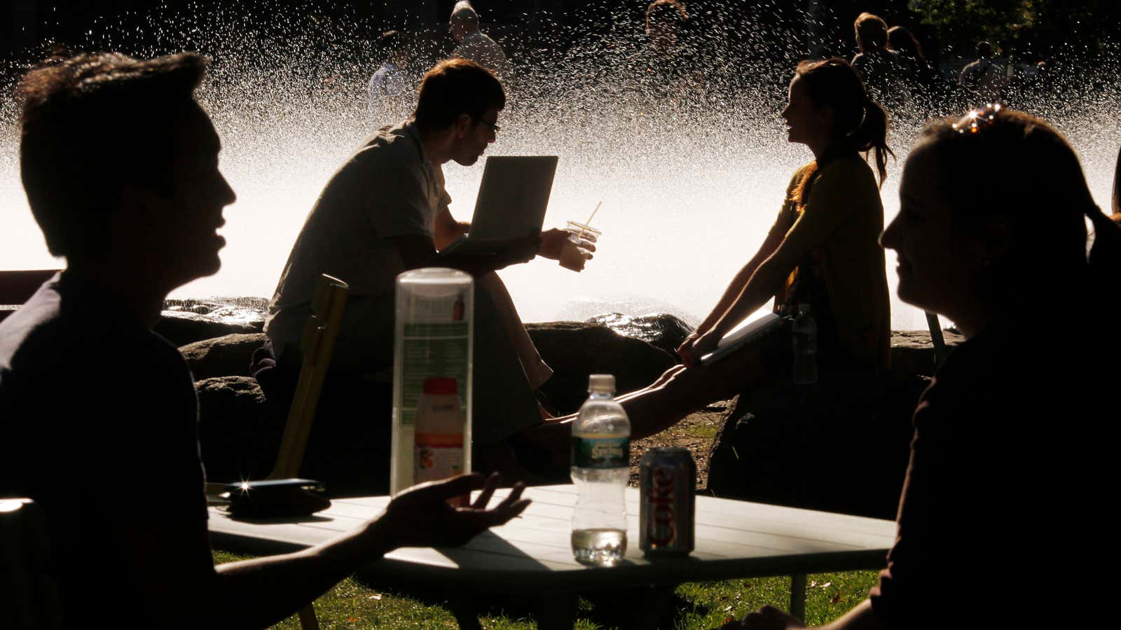 Students and visitors sit in front of a fountain at Harvard University.