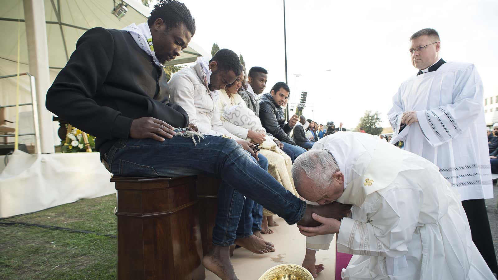 Pope Francis kisses the foot of a man during the foot-washing ritual at the Castelnuovo di Porto refugees center.
