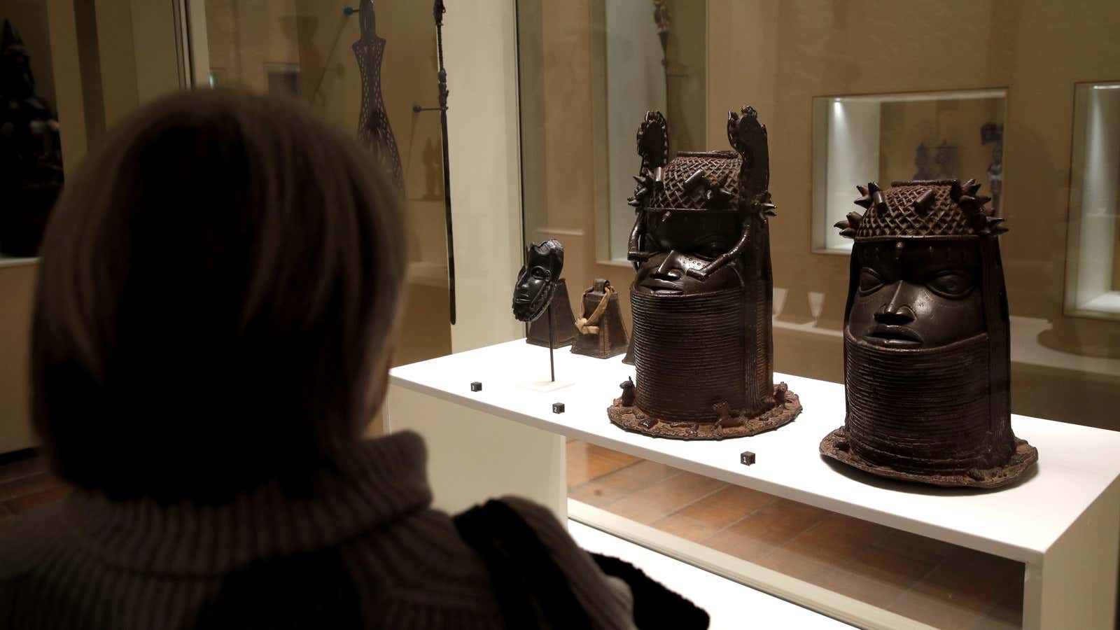 A visitor looks at two Heads of a royal ancestor (Uhunmwun Elao), from the former Benin Kingdom, a part of modern-day Nigeria displayed at the Quai Branly Museum in Paris.