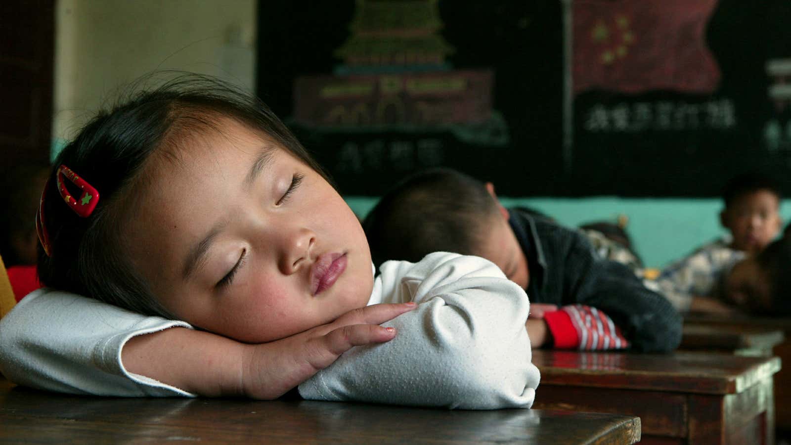Chinese school children sleep at their desks during a noon break at a private elementary school for …..