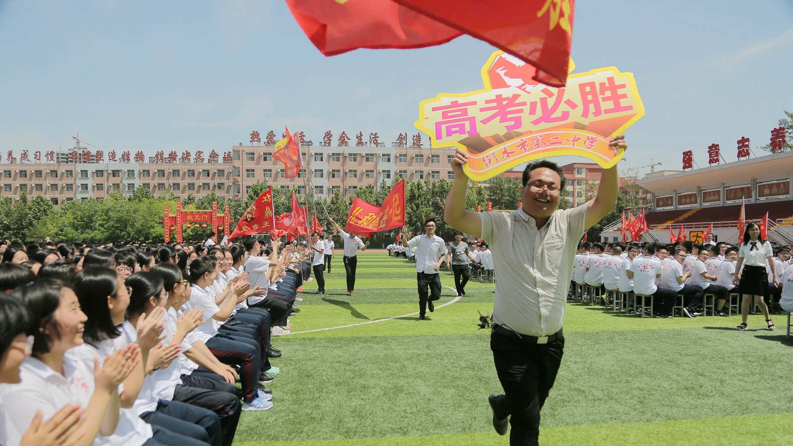 A teachur running with a sign that reads “Gaokao victory.”