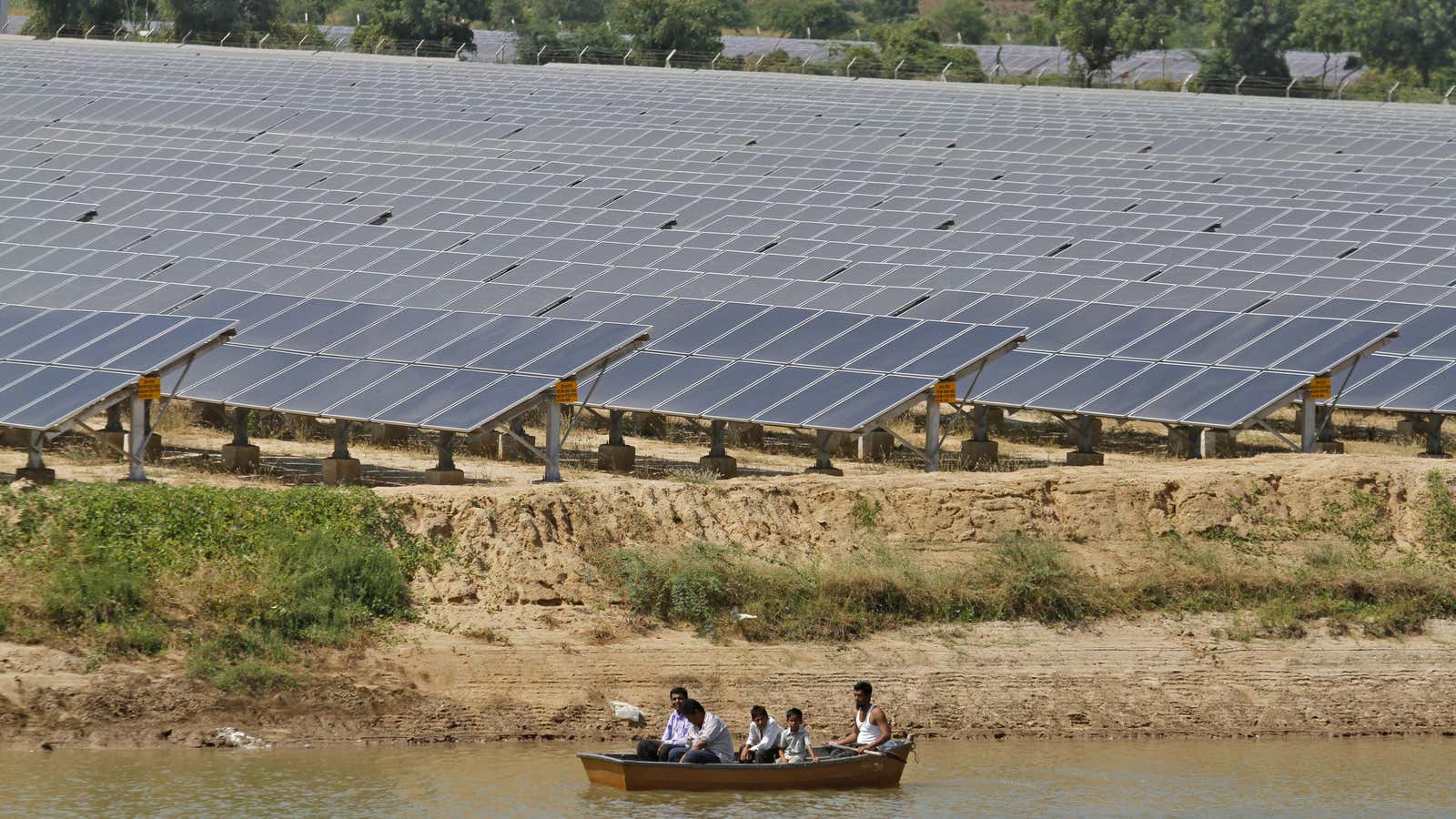 Security personnel sit in a boat as they patrol the premises of a newly inaugurated solar farm at Gunthawada village in Banaskantha district in the…