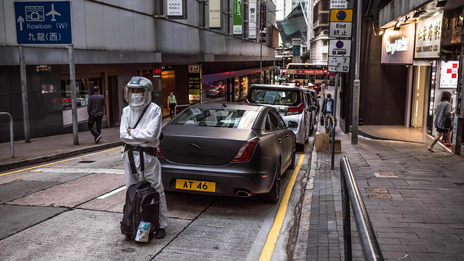 A man wearing personal protective equipment (PPE) stands on a street in Hong Kong.