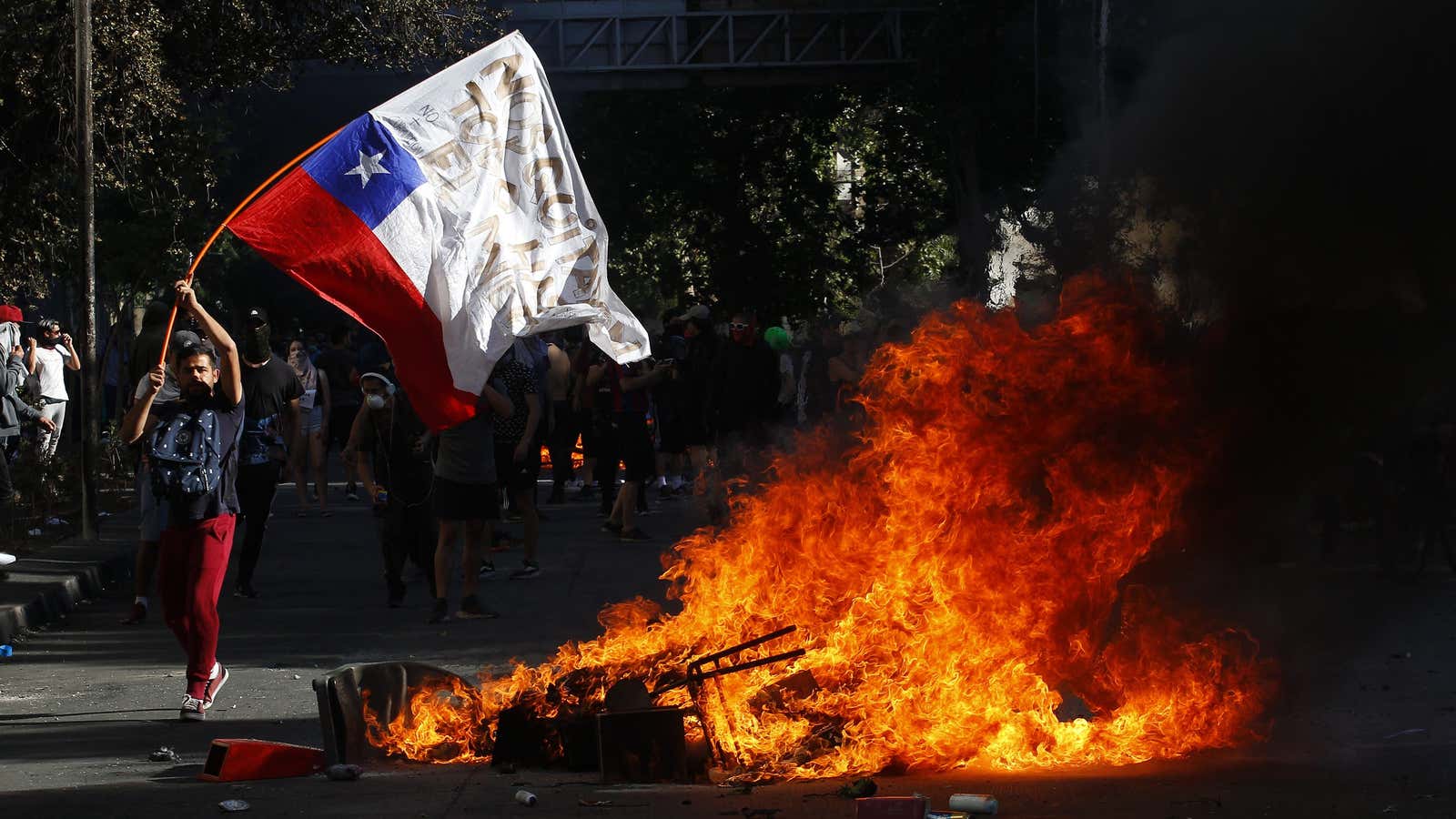 A demonstrator waves a Chilean flag next to a fire in Santiago on Oct. 21.