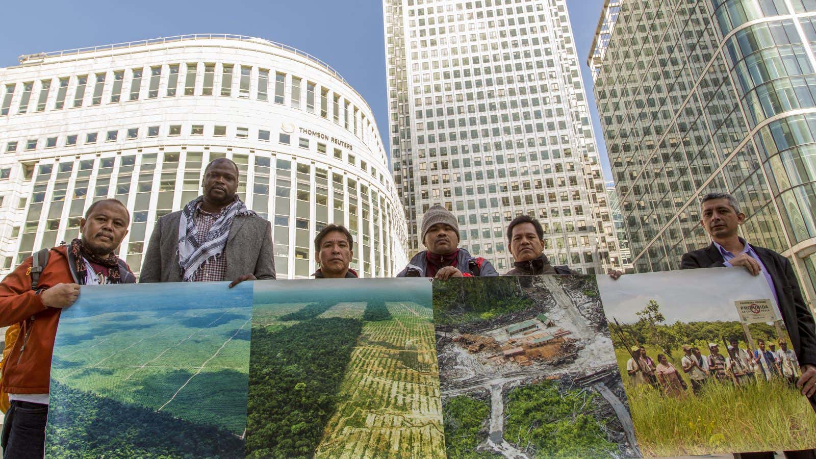 Indigenous leaders hold pictures of deforested land.