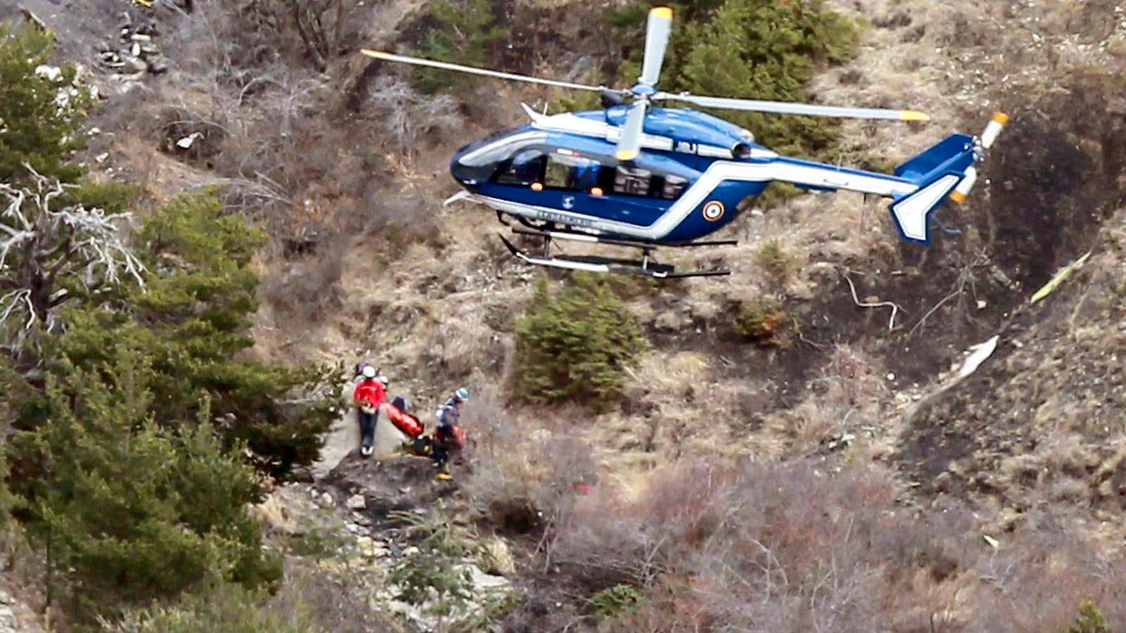 A French gendarme helicopter flies over the crash site of an Airbus A320 in the French Alps, as investigators sift through the debris.