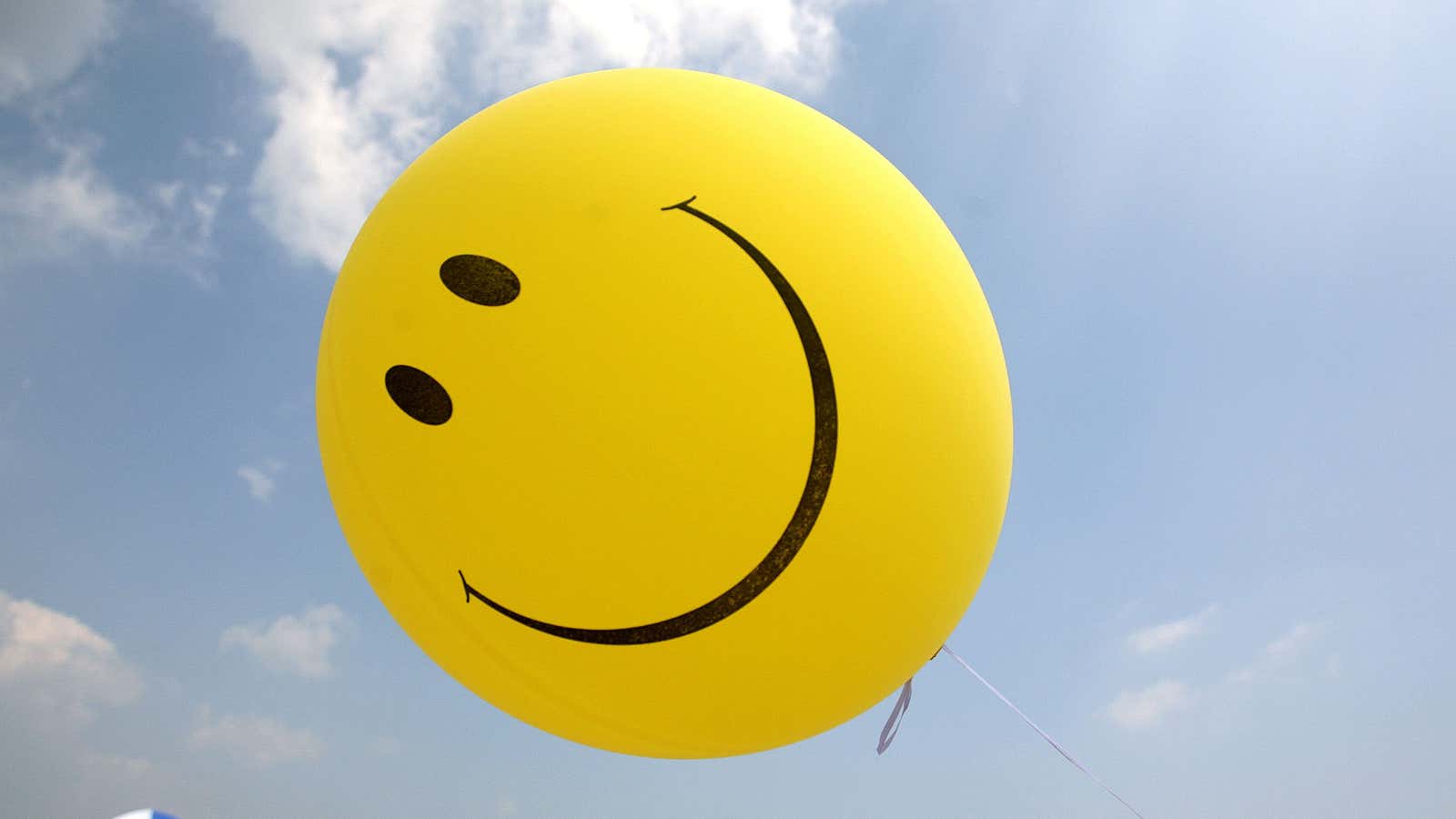 FILE – A smiley face balloon floats over Revere Beach in Revere, Mass. as beachgoers head for the water on Sunday, July 16, 2006. According…