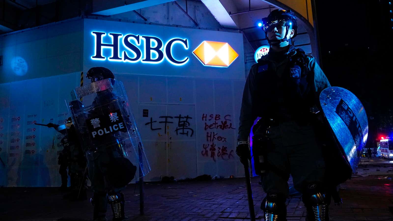 Police stand guard in front of a vandalized HSBC bank on New Year’s Day in Hong Kong, Wednesday, Jan. 1, 2020. Hong Kong toned down…
