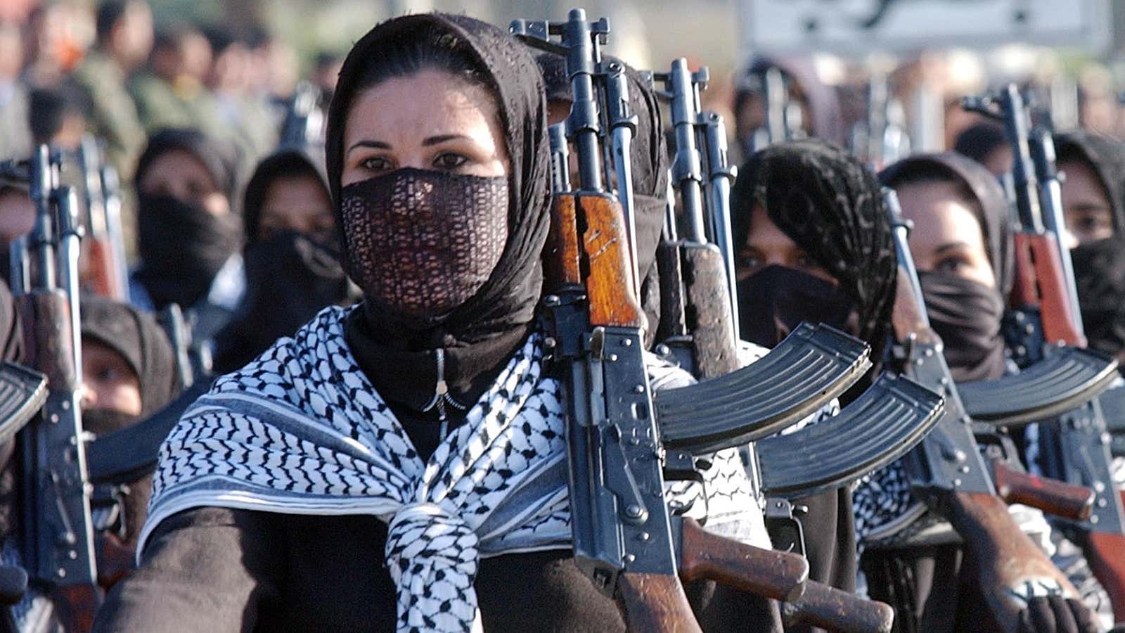 Iraqi women hold AK-47 assault rifles and march during a military parade in Diala province, northeast of Baghdad, Iraq on Jan. 7, 2003.