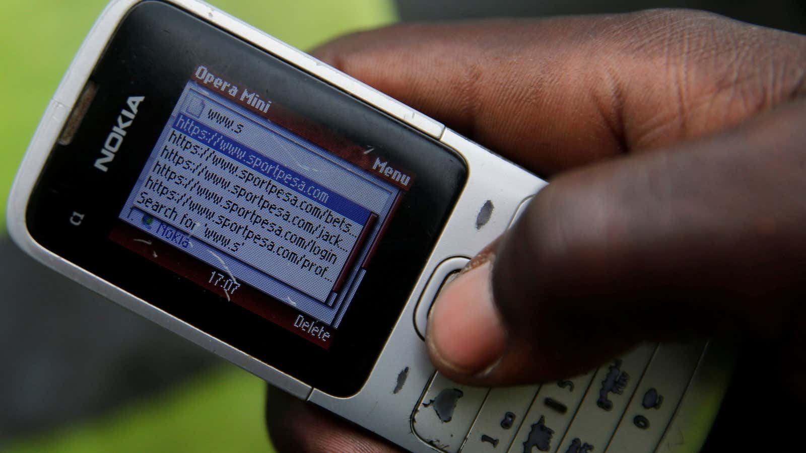 A gambler uses his cell phone to launch the an online betting link in Kenya