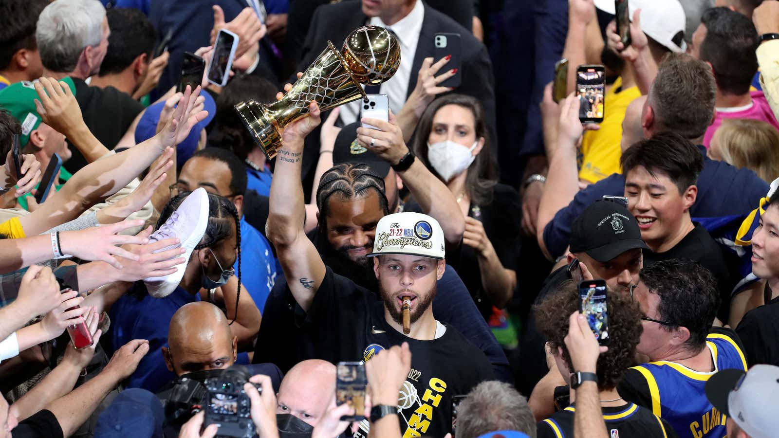 Warriors guard Steph Curry surrounded by fans as he holds up his Most Valuable Player trophy at the NBA Finals.