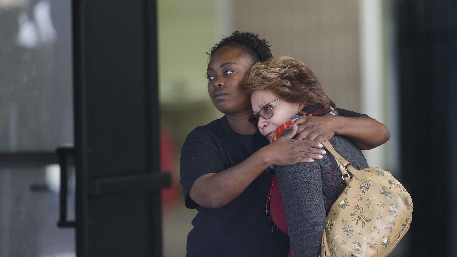 Two women embrace at a community center where family members are gathering to pick up survivors.