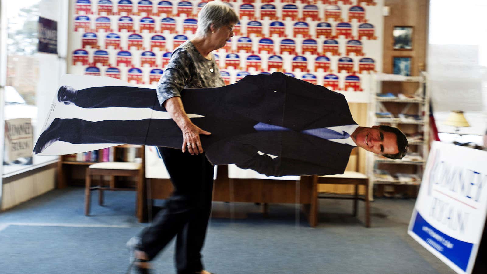 A volunteer puts away a life-size cut out of Mitt Romney