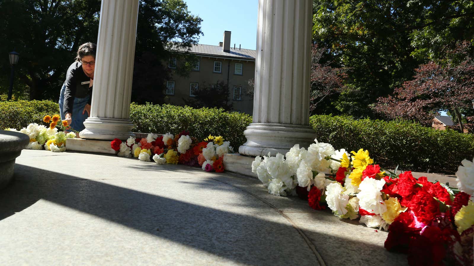A woman places flowers at UNC’s Old Well after the death of former men’s basketball coach Dean Smith.