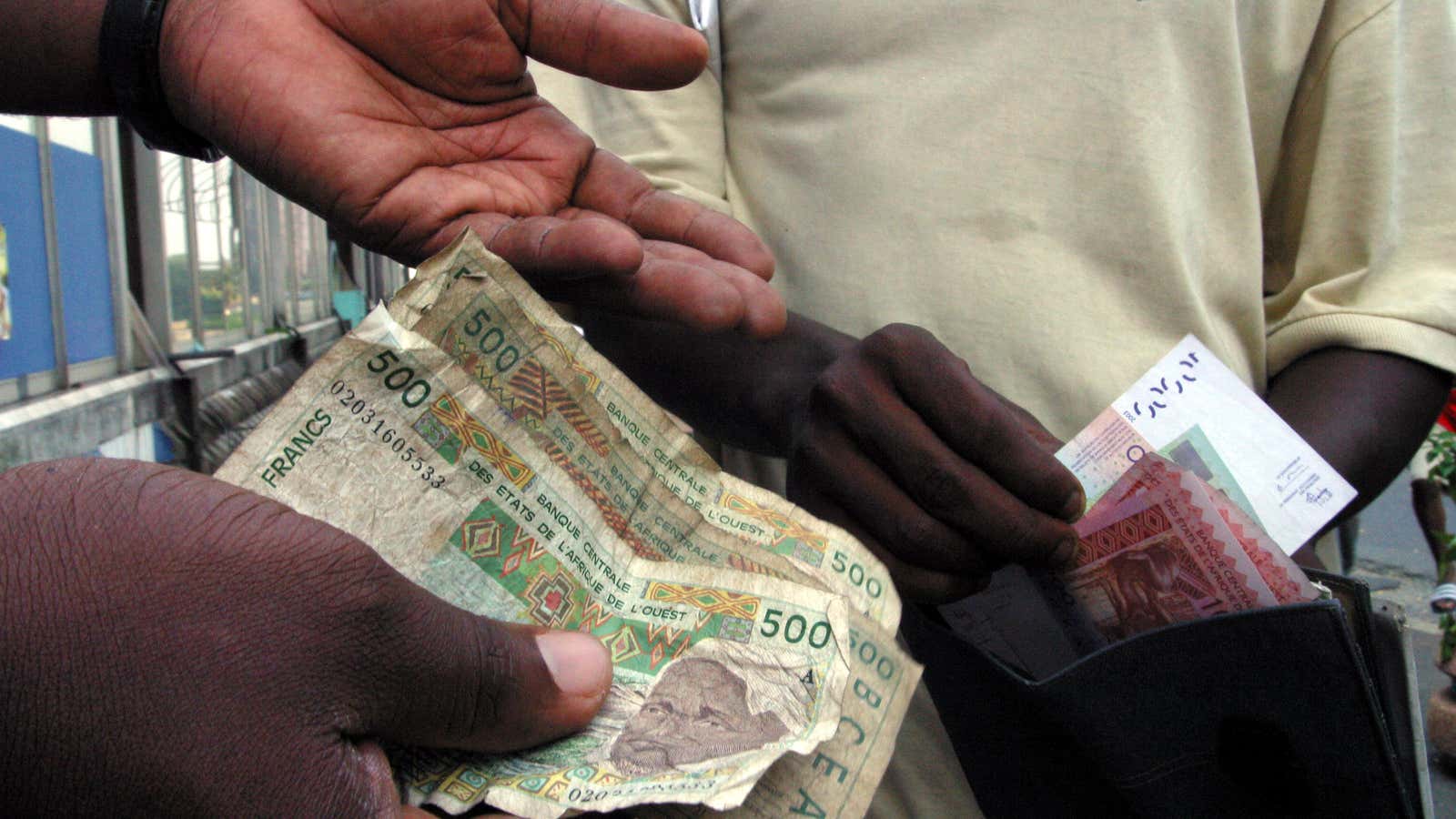 People exchange money in Abidjan, December 31, 2004. Across West Africa, people queued at bank counters on Friday to swap their grubby old CFA franc…