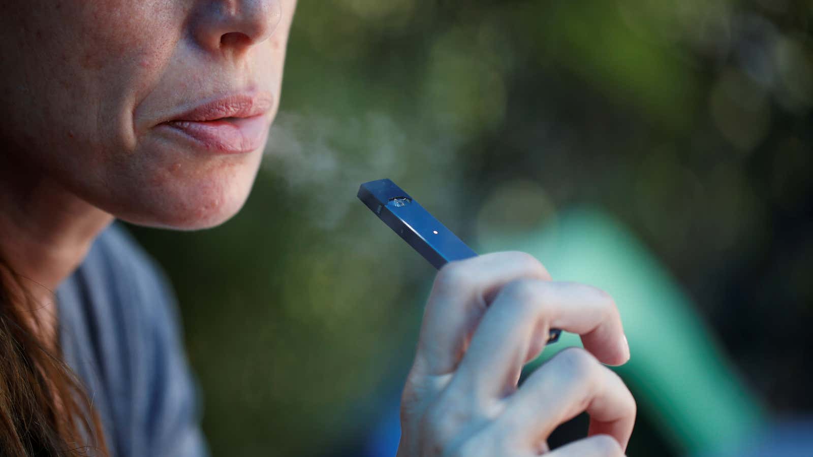 A woman smokes a Juul e-cigarette in this posed picture.