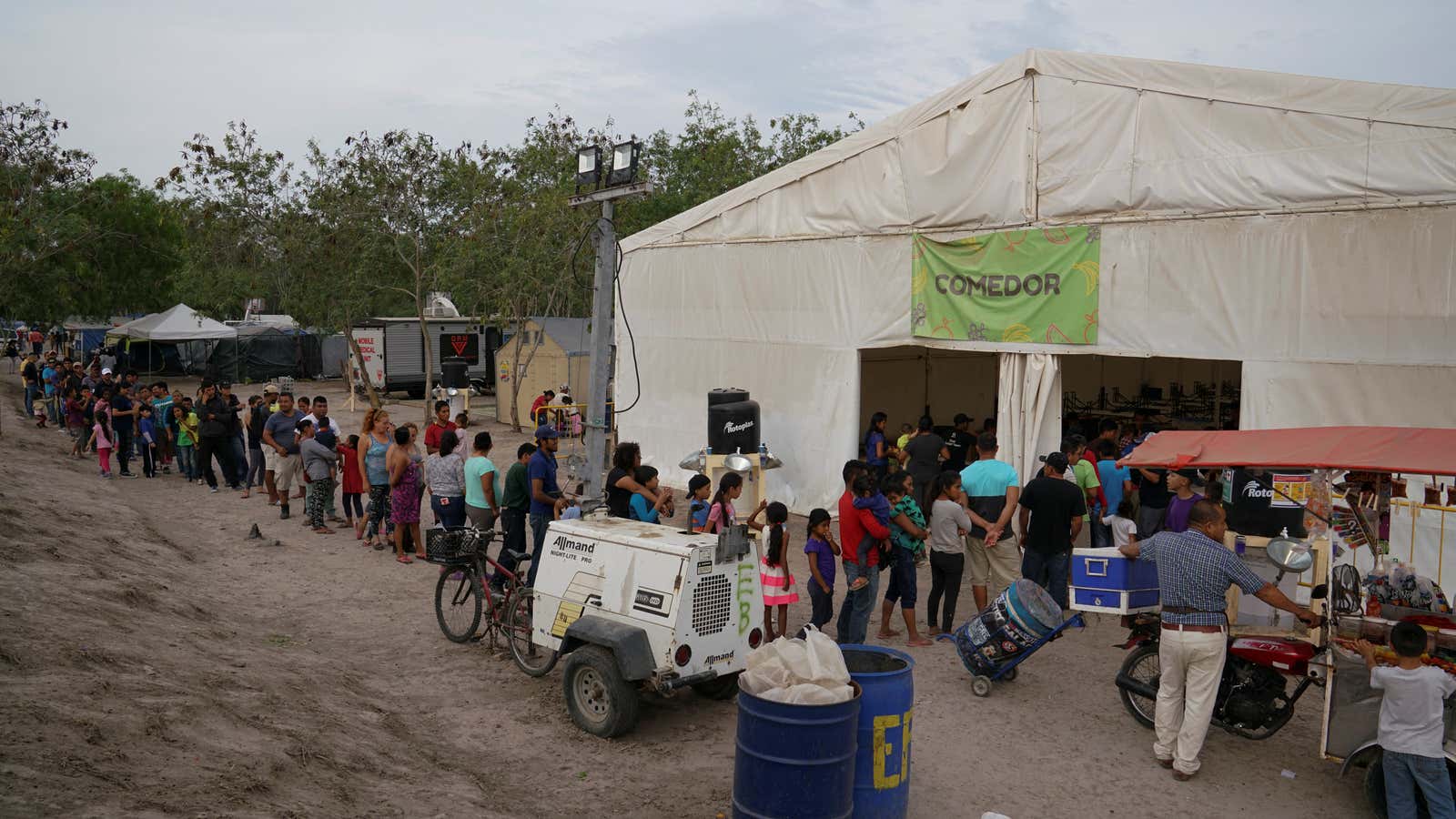 People wait in line for a meal at the Matamoros migrant encampment.
