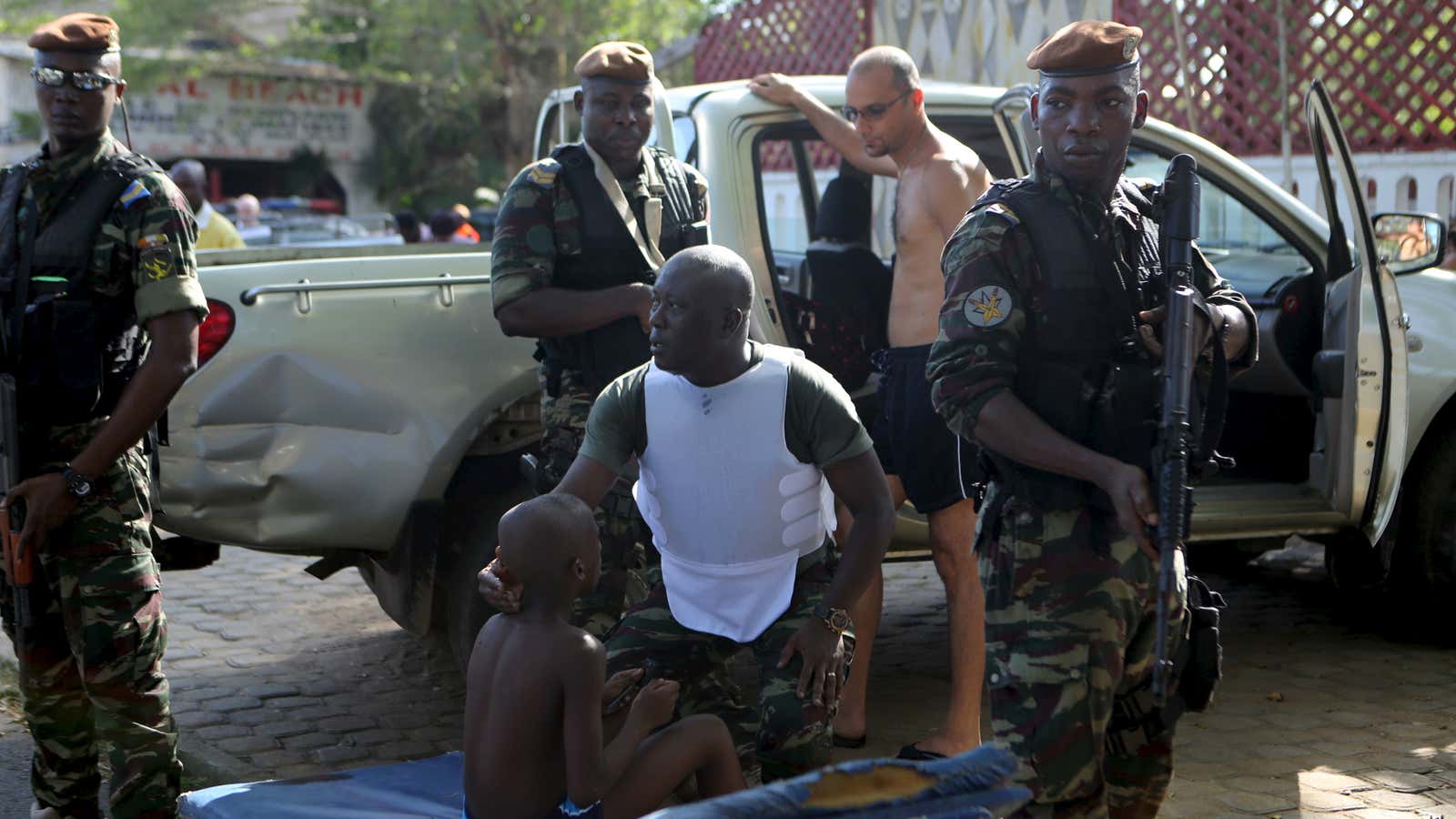 A soldier comforts an injured boy in Bassam, Ivory Coast, following an attack that left 18 people dead.