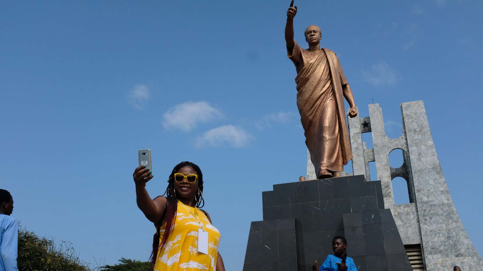 A member of an African American heritage tour group in Ghana takes a selfie under the statue of Ghana’s first president Kwame Nkrumah in Accra, Aug. 7, 2019