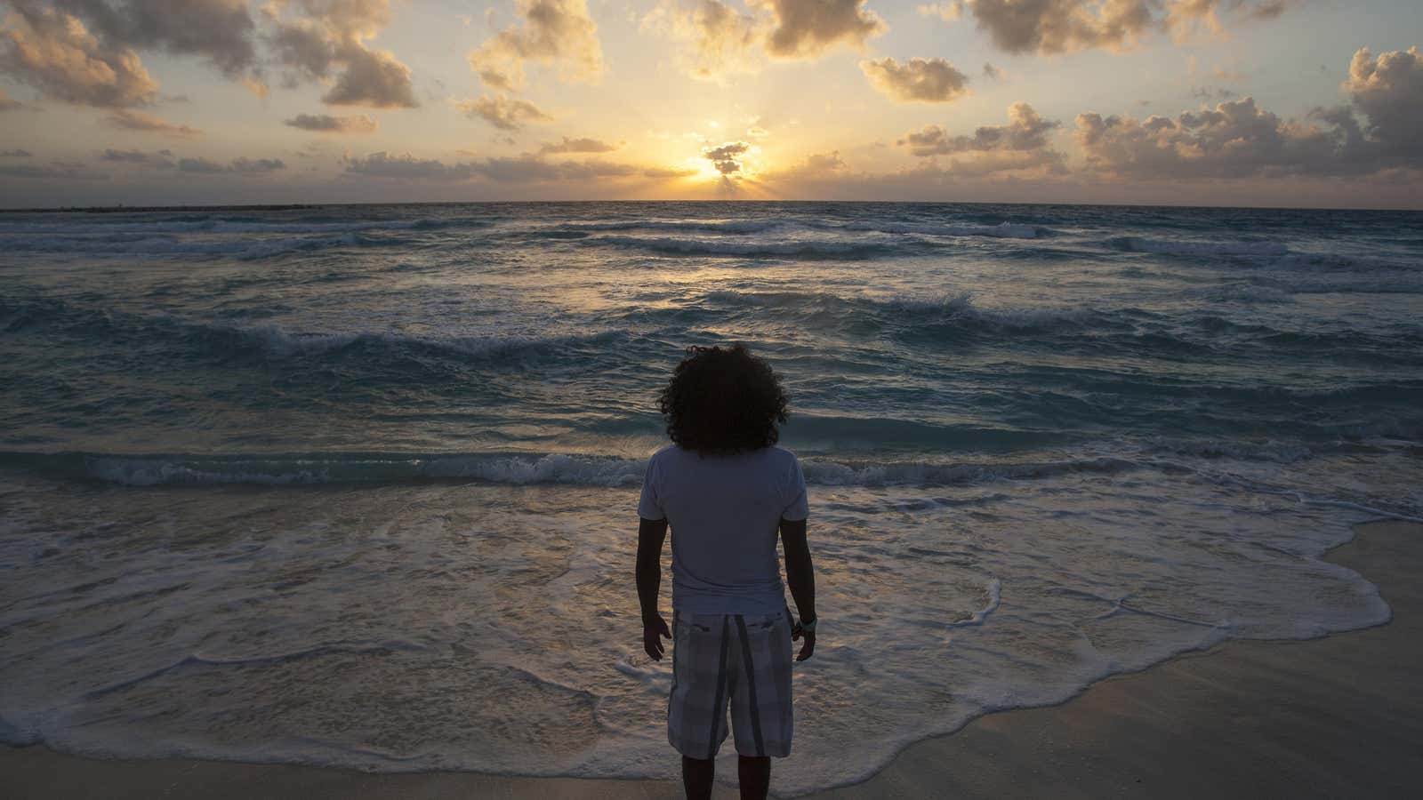A man watches the sunrise on New Year’s Day at Gaviota Azul beach in Cancun January 1, 2014.