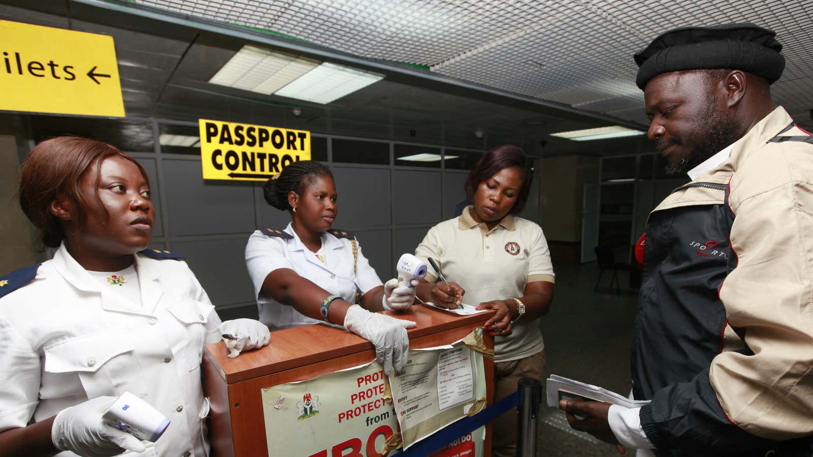 Health port officials uses a thermometer to screen passengers at the arrival hall of Murtala Mohammed International airport in Lagos, Nigeria Monday, Oct. 20, 2014.