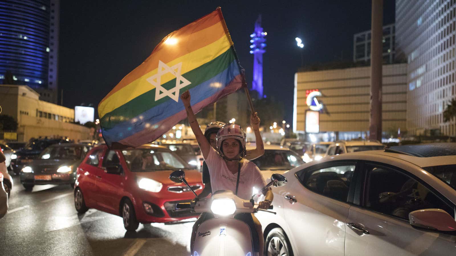 An Israeli woman holds a rainbow flag with a Star of David during a demonstration in Tel Aviv, Thursday, July 20, 2017. Several thousand people are protesting in Tel Aviv against an Israeli government ban on adoptions by same-sex couples. (AP Photo/Dan Balilty)