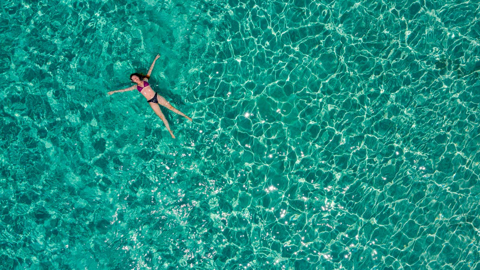 An aerial view shows a woman enjoying the sea on a beach of the small island of Chrysi, south of Crete on July 26, 2020.…