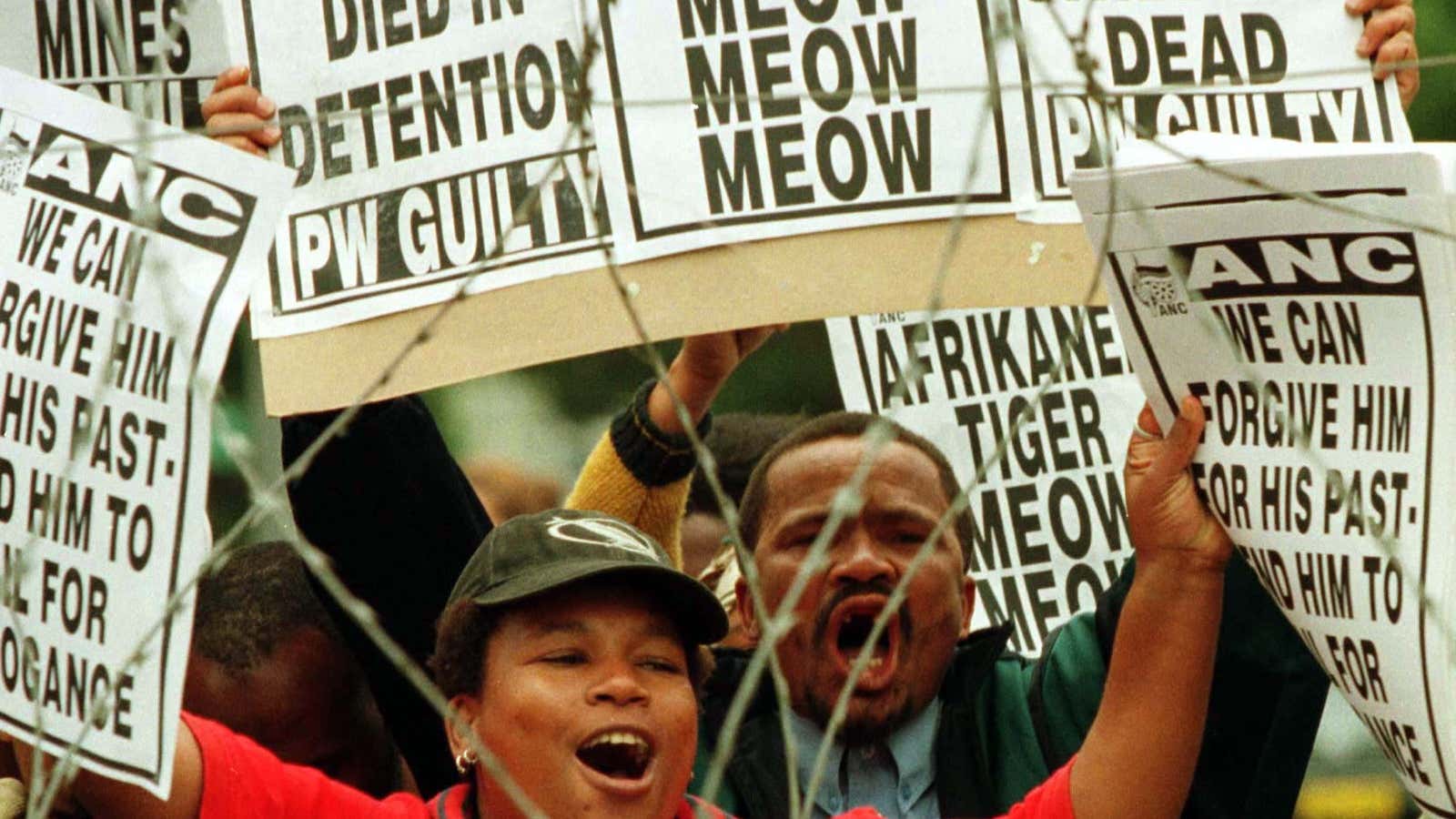 Demonstrators protest as South Africa’s last hardline apartheid president, PW Botha, appears in court on charges of defying the country’s truth body and said afterwards he was unrepentant about his past actions.
