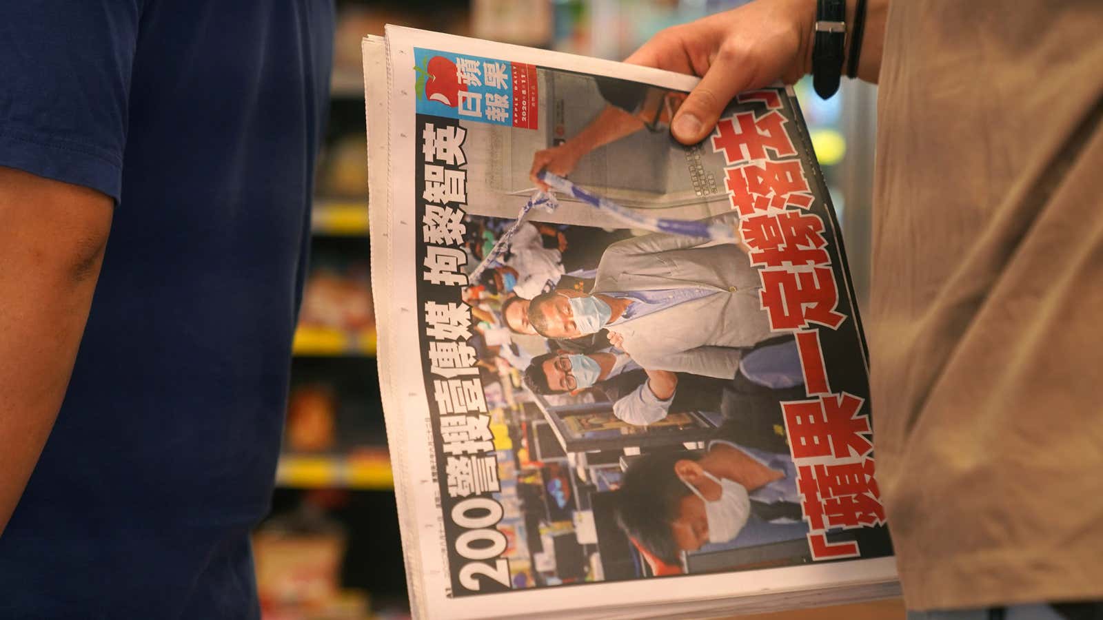 A man waits to pay for a Apple Daily newspaper with the headline “Apple Daily will fight on” after media mogul and founder of Apple…