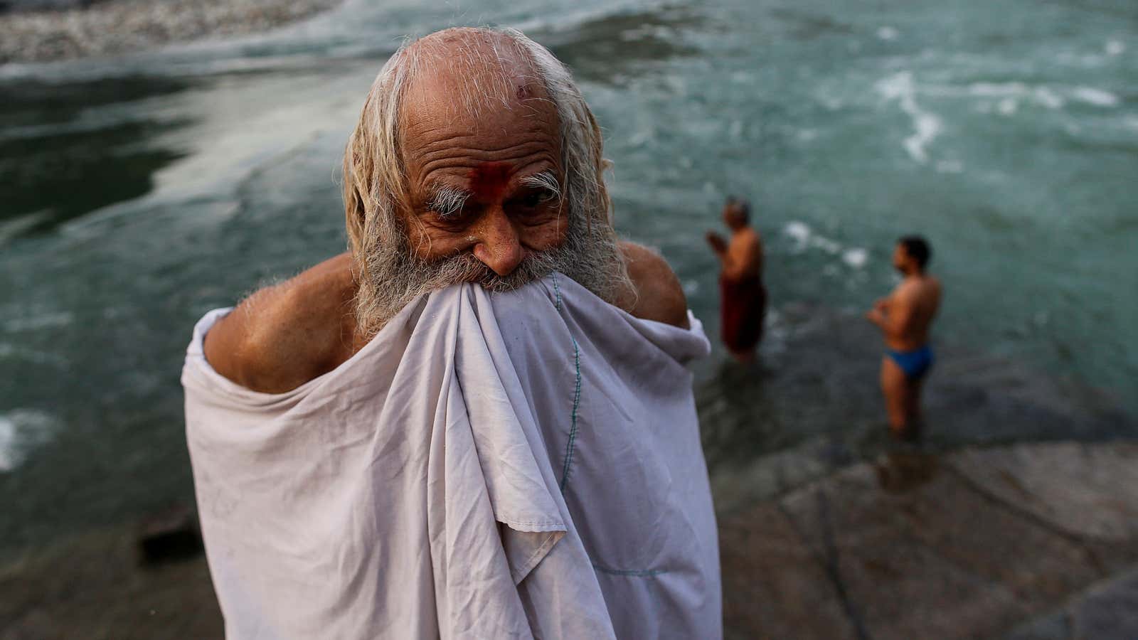 A Hindu devotee holds up his clothes after taking a dip in the river Ganges in Devprayag, India.