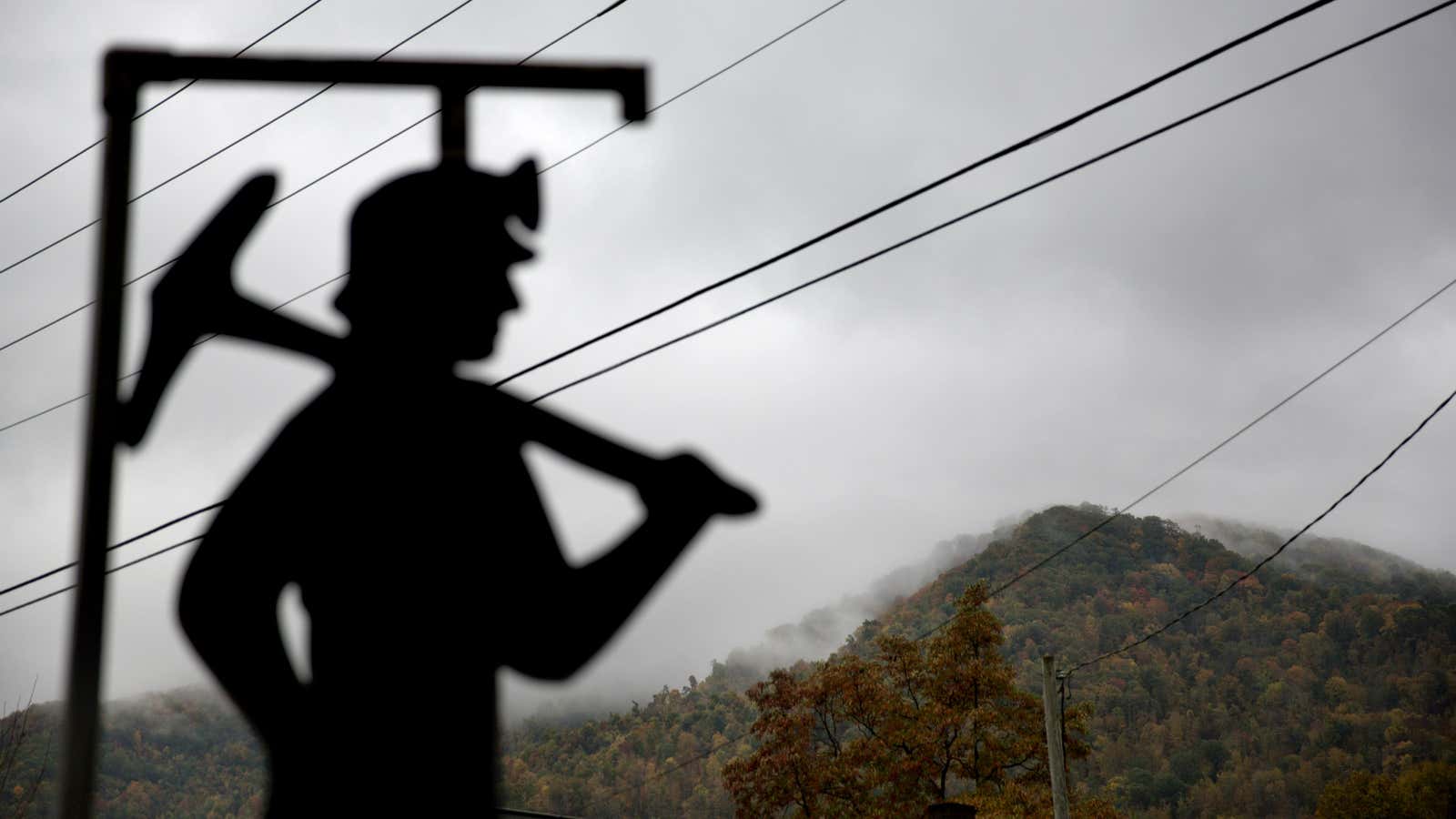 In this Oct. 16, 2014 photo, fog hovers over a mountaintop as a cut out of a coal miner stands at a memorial to local…