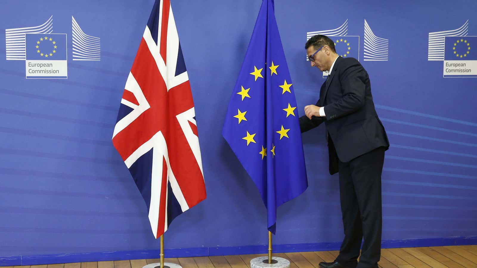 A employee of the EU Commission arranges the British Union flag and the European Union flag.
