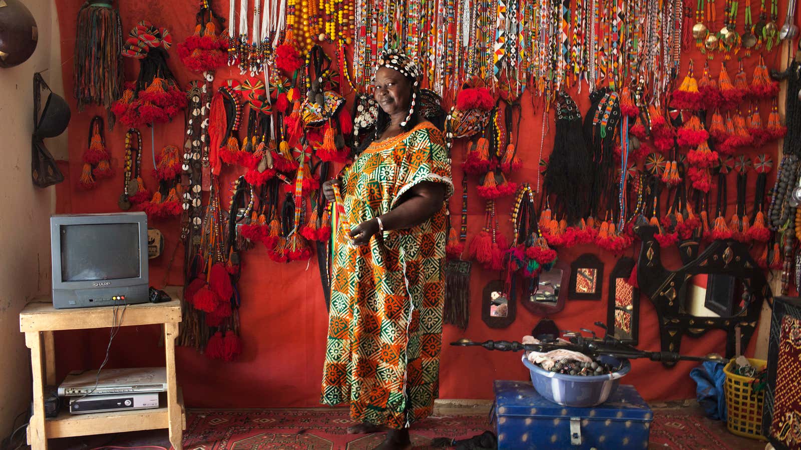 A local artisan stands in front of her store featuring numerous ornaments made of beads in Gao, Mali