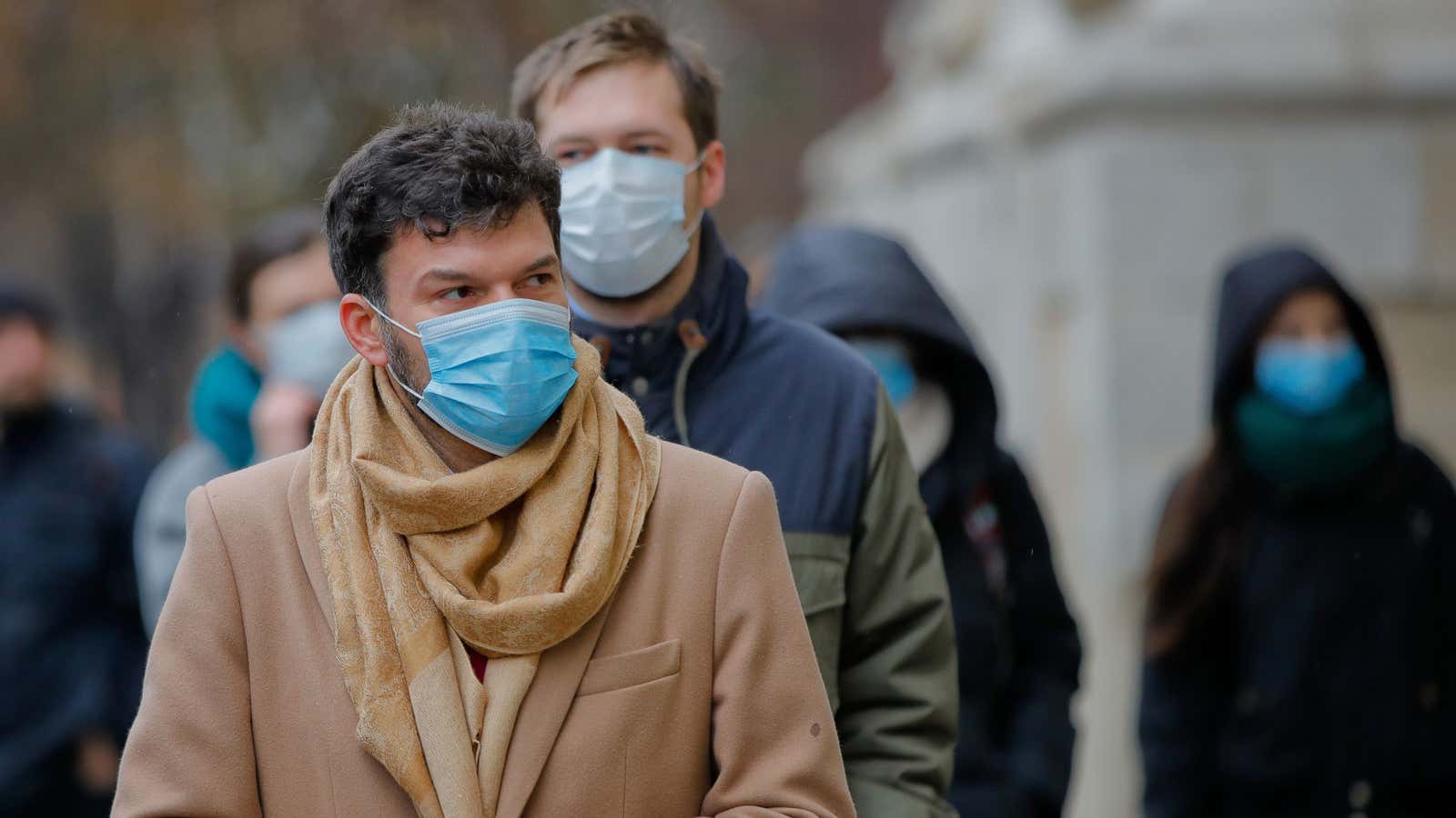 People walk wearing masks during an anti-pollution protest outside the city hall in Bucharest, Romania, Wednesday, Dec. 12, 2018.