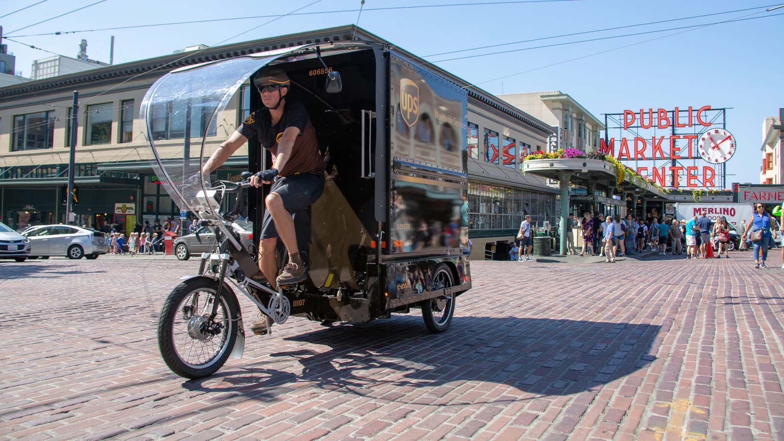 A UPS e-bike delivery person rides through the bumpy brick road in Seattles Pike Place Market.