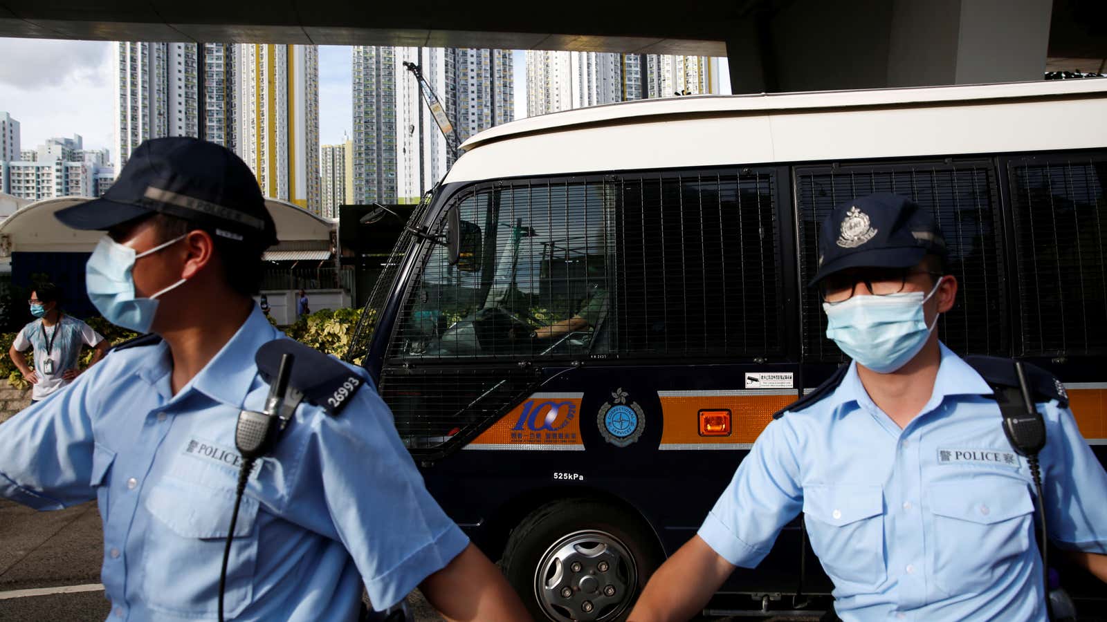Police officers escort a prison van which is carrying Tong Ying-kit, the first person charged under the new national security law, as he leaves West…