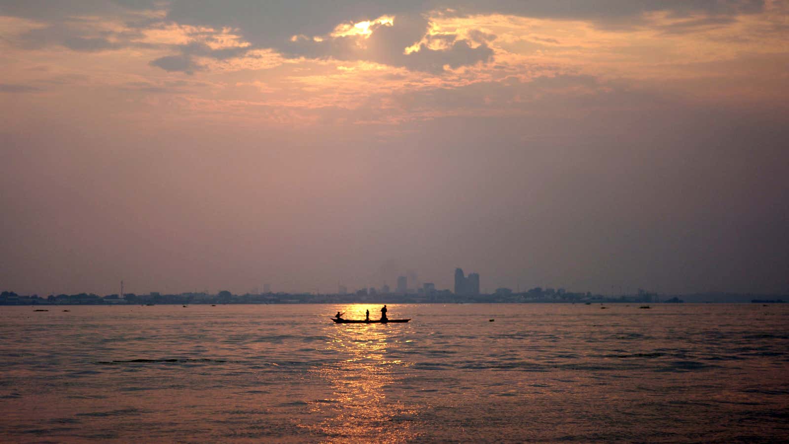 A wooden pirogue sails at dusk on the Congo River against the backdrop of high rises in the Democratic Republic of Congo’s capital Kinshasa, March…