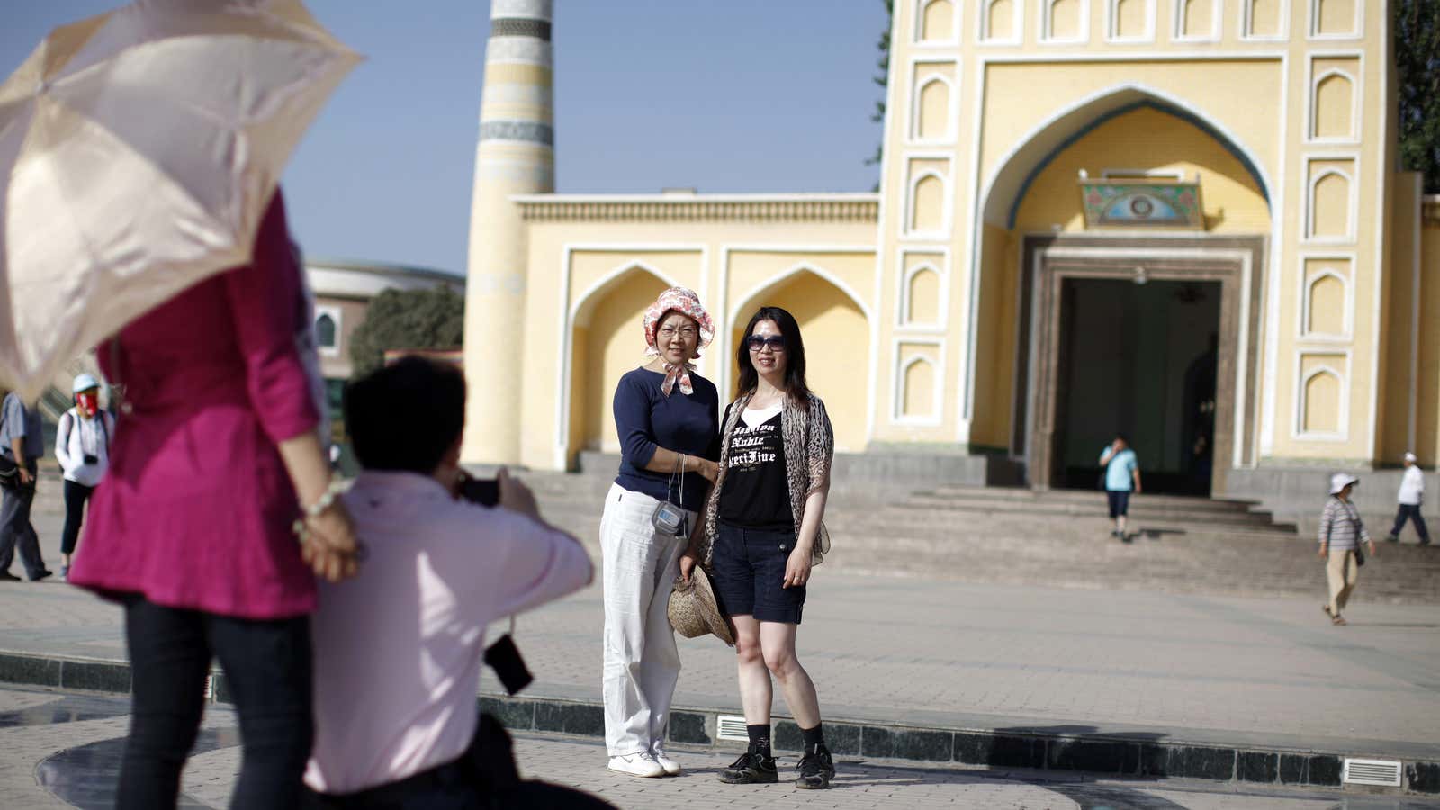 Chinese tourists pose for a picture in front of a mosque.
