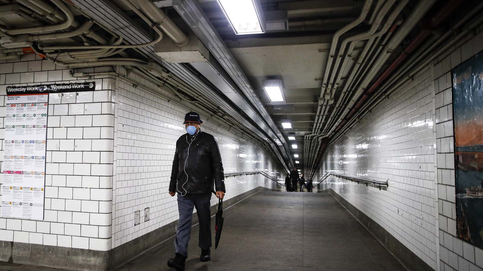 A subway customer walks through an empty underground passage in Brooklyn, New York, Monday, March 16, 2020.
