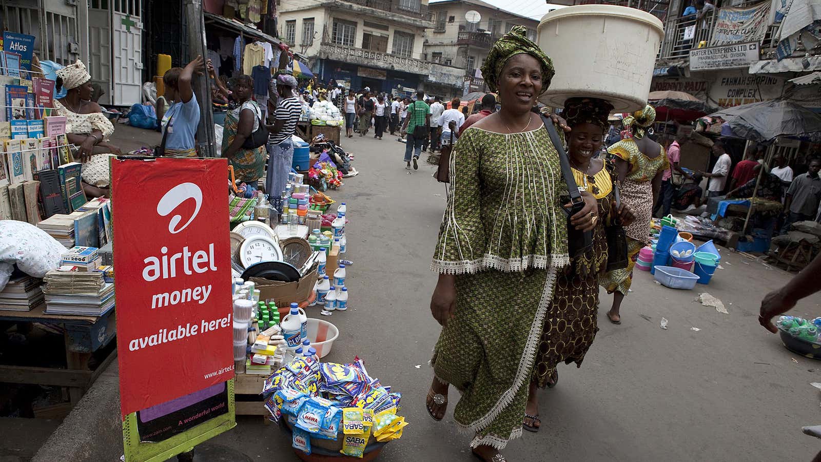 A woman walks past a sign advertising the mobile banking service Airtel Money in Freetown.