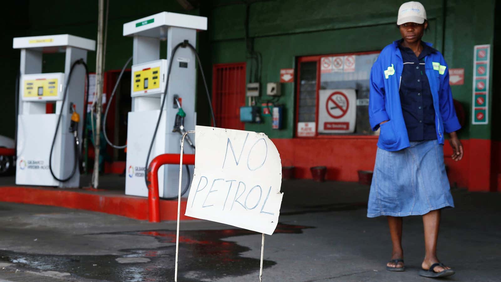 A woman walks past a “No Petrol” sign at a fuel station in Harare, Zimbabwe, Oct. 9.