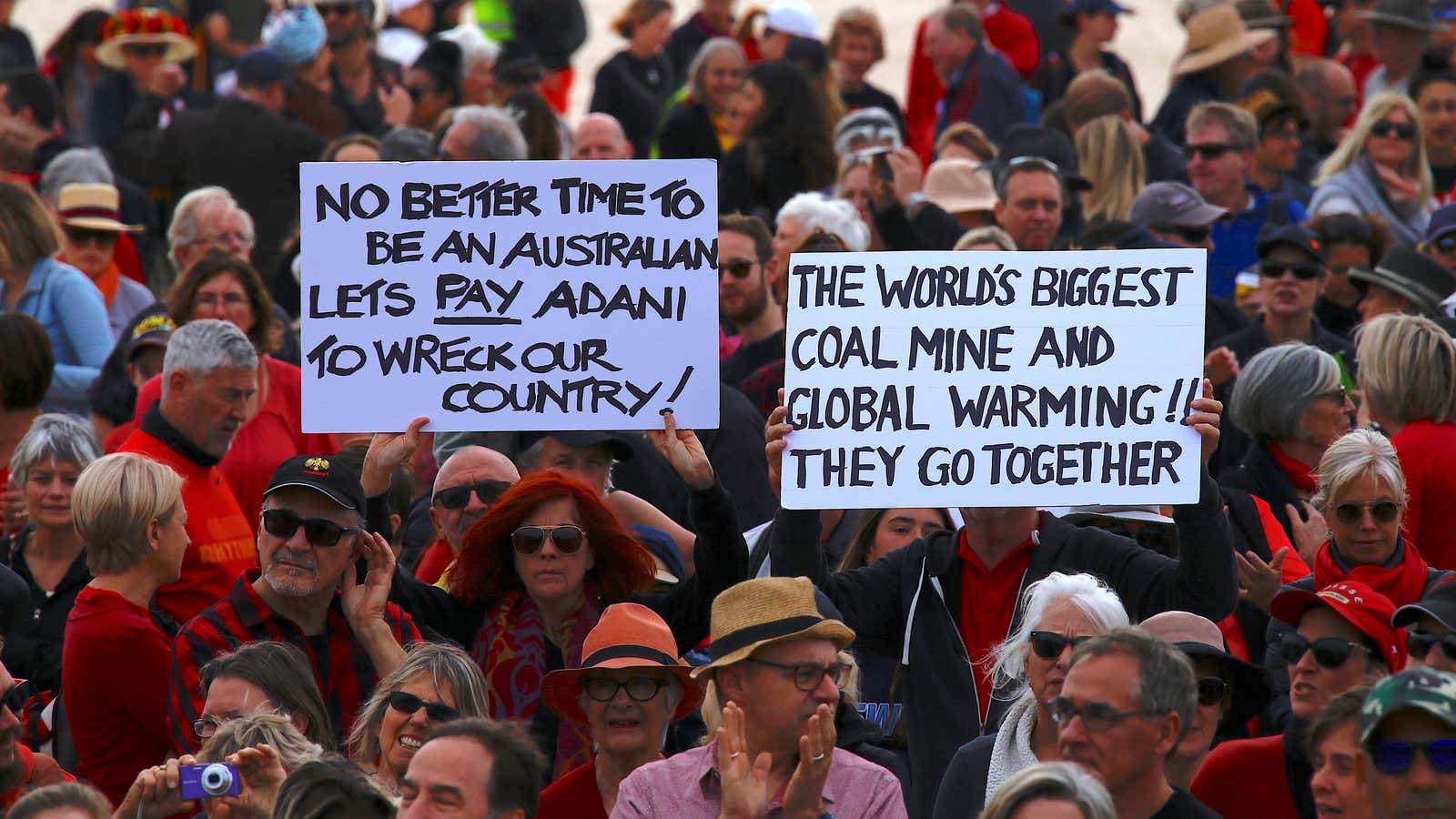 Protesters hold signs as they participate in a national Day of Action against the Indian mining company Adani’s planned coal mine project in north-east Australia,…
