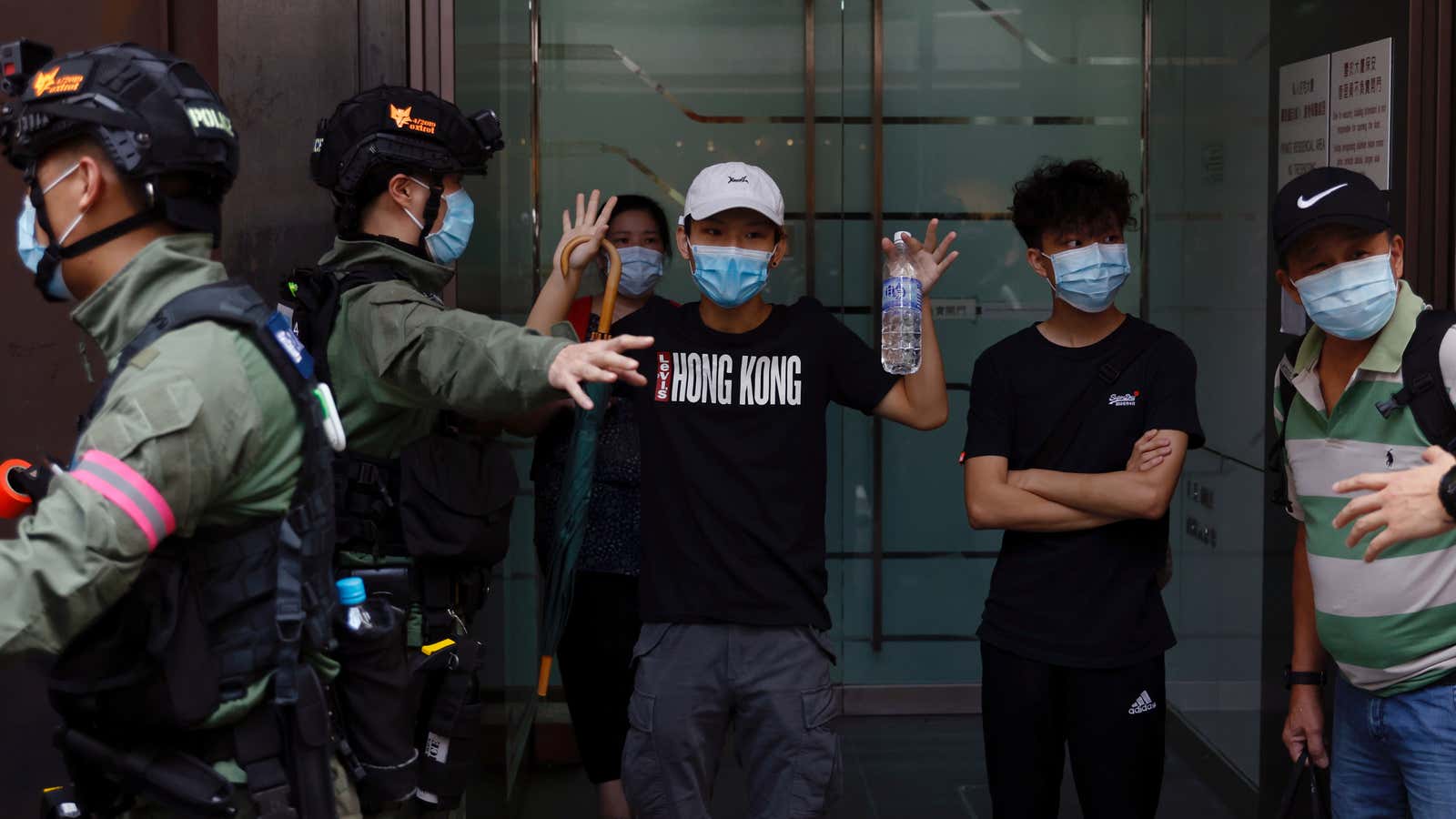 A man raises his hands as police stop to search him during a protest urging the release of twelve Hong Kong activists detained on the…